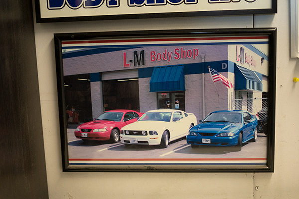 Framed photo of the L-M Body Shop building with classic Mustangs out front