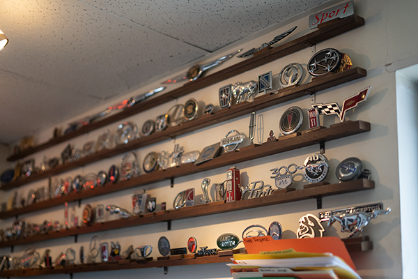 Wall of vintage hubcaps and emblems inside the L-M Body Shop office